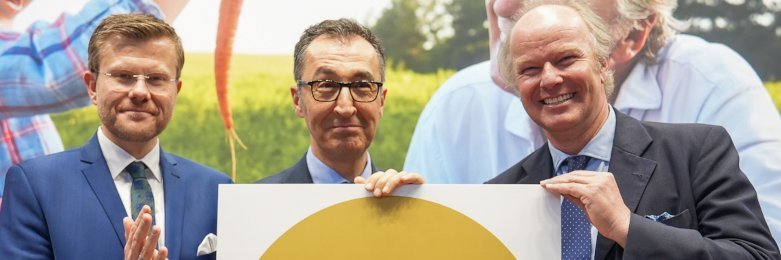 Stefan Hipp, Cem Özdemir und Marcus König halten das Bio-Logo in Gold