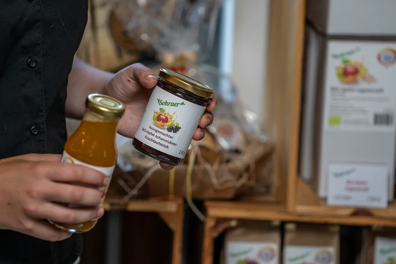 Hände wie sie ein Glas Marmelade und ein Fläschen Saft in der Hand halten. Klick führt zu Großansicht.