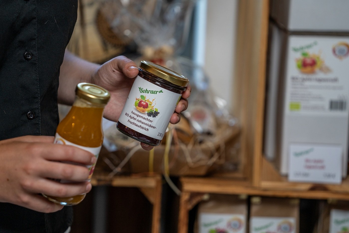 Hände wie sie ein Glas Marmelade und ein Fläschen Saft in der Hand halten. Klick führt zu Großansicht.