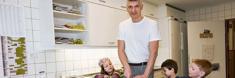 Mann mit Kindern in der Küche.