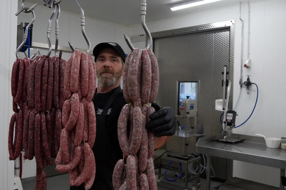 Mann mit frischer Wurst in Metzgerei. Klick führt zu Großansicht in einer Lightbox. Zum Schließen der Lightbox ESC drücken.