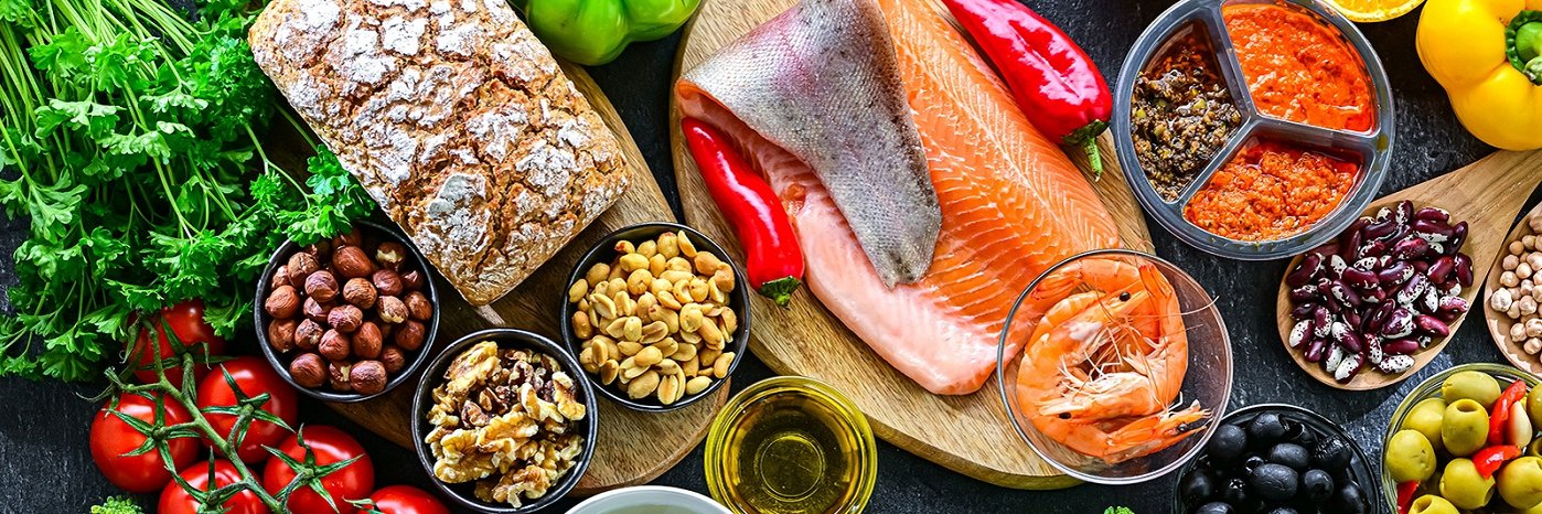 Verschiedene Lebensmittel wie Gemüse, Brot, Nüsse, Fisch und Öl.