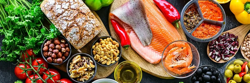 Verschiedene Lebensmittel wie Gemüse, Brot, Nüsse, Fisch und Öl.