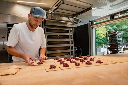 Ein Mann beim Füllen von Teig in einer Backstube.