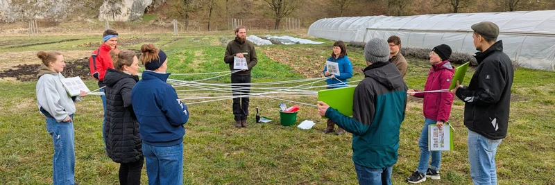 Auszubildende spielen ein Lernspiel auf einer Wiese.