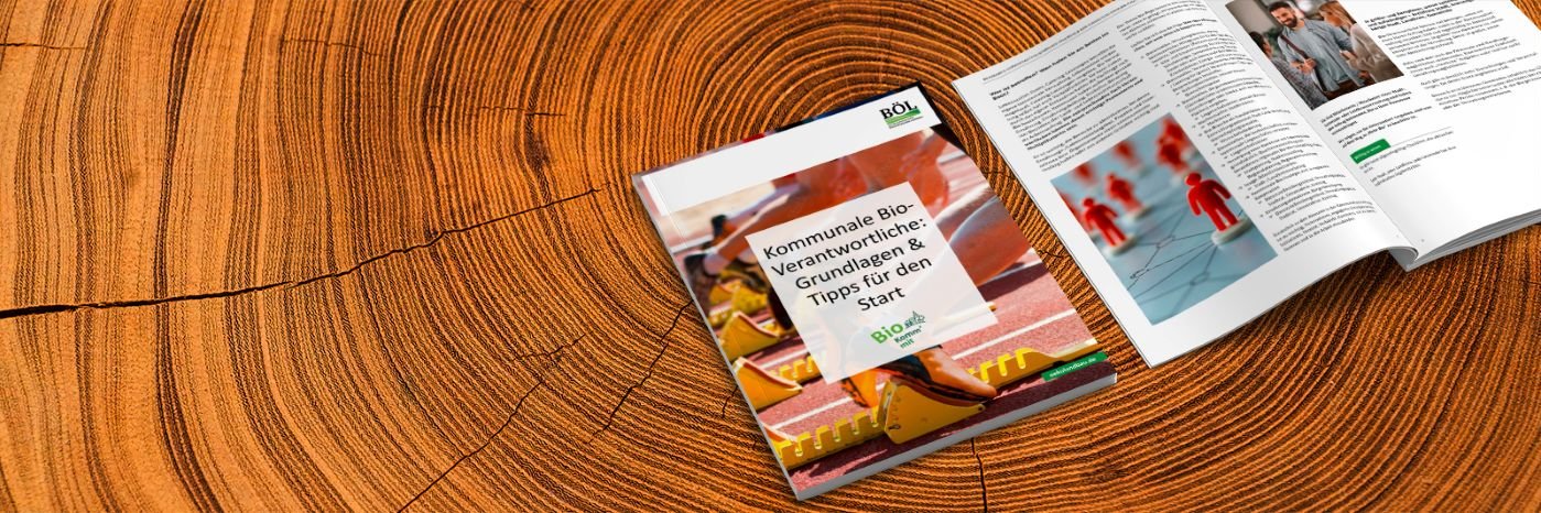 Zwei Broschüren von Bio Komm' mit auf einem Holztisch.