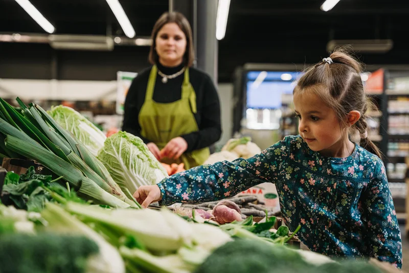 Kind in Supermarkt greift zu Gemüse. Klick führt zu Großansict in neuem Fenster.
