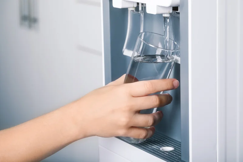 Ein Hand füllt ein Glas mit Wasser