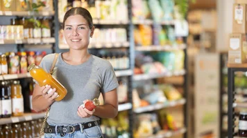 Junge Frau kauft Saft im Laden. 
