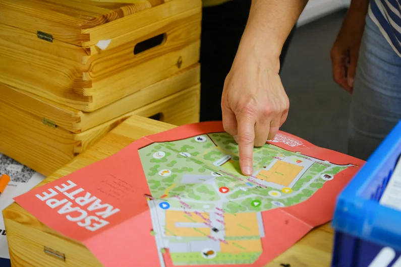 Eine Hand zeigt mit dem Finger auf die Escape Karte