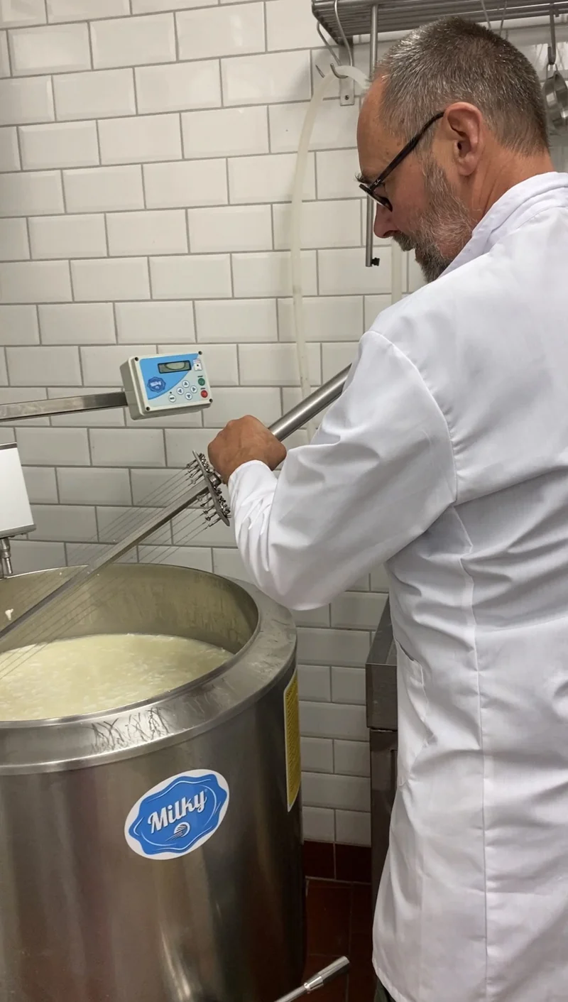 Mann beim Käserühren. Klick führt zu Großansicht.