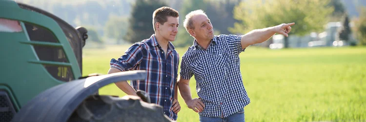 zwei Männer stehen auf dem Feld. Der ältere Mann erklärt etwas und zeigt in die Ferne
