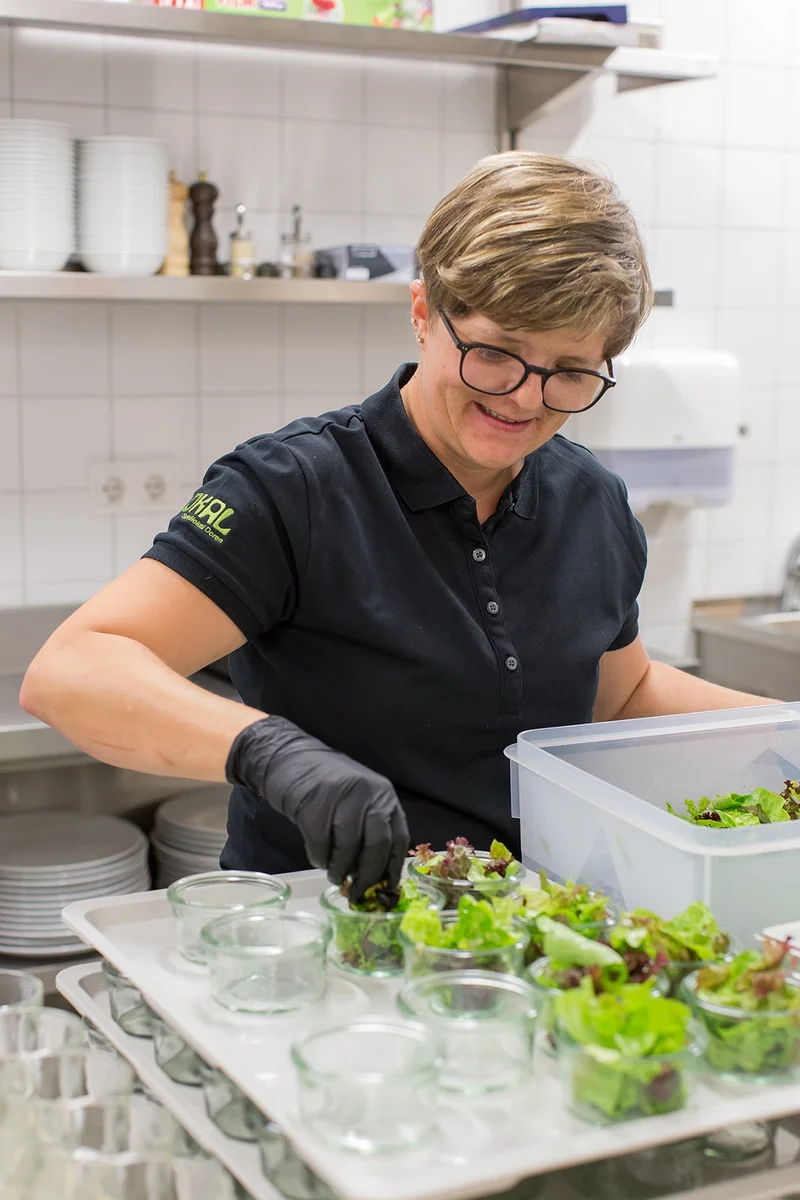 Küchenleiterin Natalie Türtscher, Schulküche Doren, stellt Salatschälchen bereit.