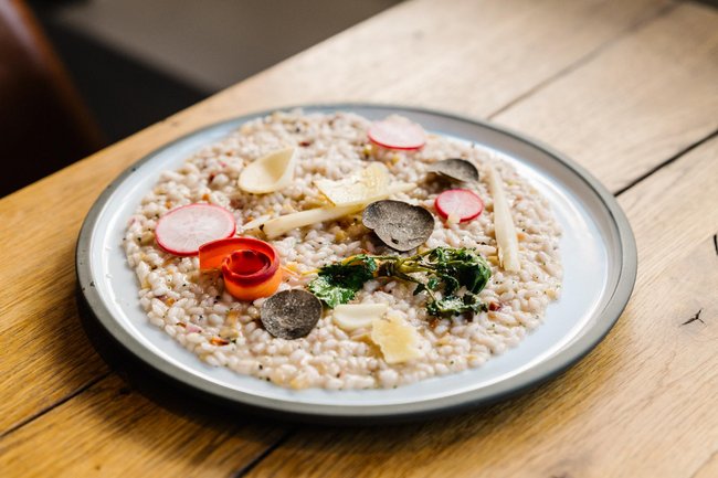 Getrüffeltes Risotto mit Wilkenshoffer Rüben und Backensholzer Deichkäse angerichtet auf einem Teller.