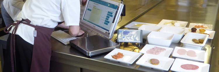 Küchenpersonal bei der digitalen Erfassung von Daten zu Lebensmittelabfällen in der Küche. 