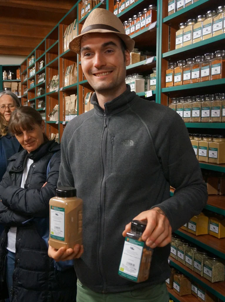 Mann mit Hut mit Bio-Gewürzen in der Hand. Klick führt zu Großansicht in neuem Fenster.