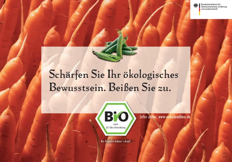 Plakat mit Möhren im Hintergrund, davor steht "Schärfen Sie Ihr ökologisches Bewusstsein. Beißen Sie zu."