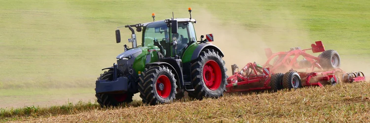 Traktor mit Scheibeneggen auf dem Feld