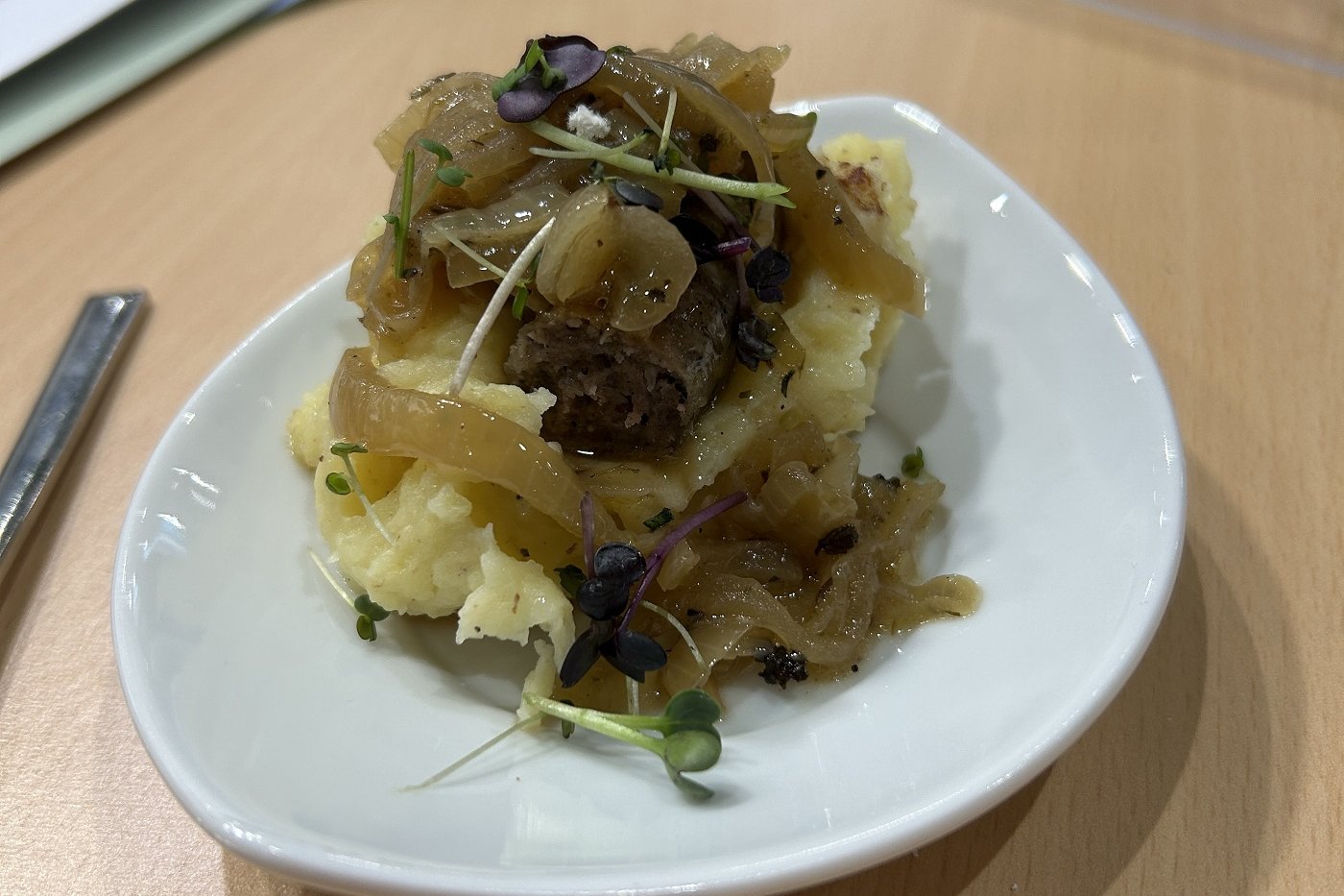 Schafsbratwurst mit Kartoffelstampf und Schmelzzwiebeln auf einem Teller angerichtet. Foto: BLE