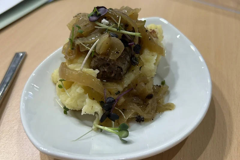 Schafsbratwurst mit Kartoffelstampf und Schmelzzwiebeln auf einem Teller angerichtet. Foto: BLE
