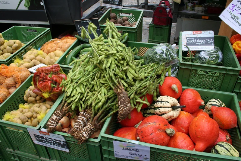 Gebündelte Edamame auf Gemüsekisten eines Wochenmarkt-Stands. Klick führt zu Großansicht.