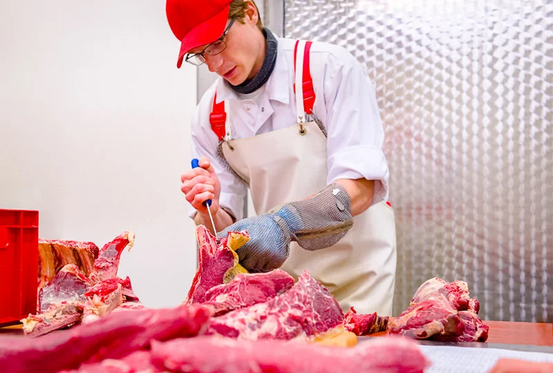 Metzger zerteilt Fleisch. Klick führt zu Großansicht im neuen Fenster.