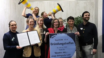 Gruppenfoto von Menschen, die Plakat und Textdokumente in die Kamera halten.