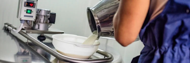 Mann gießt Milch aus Milchkanne.