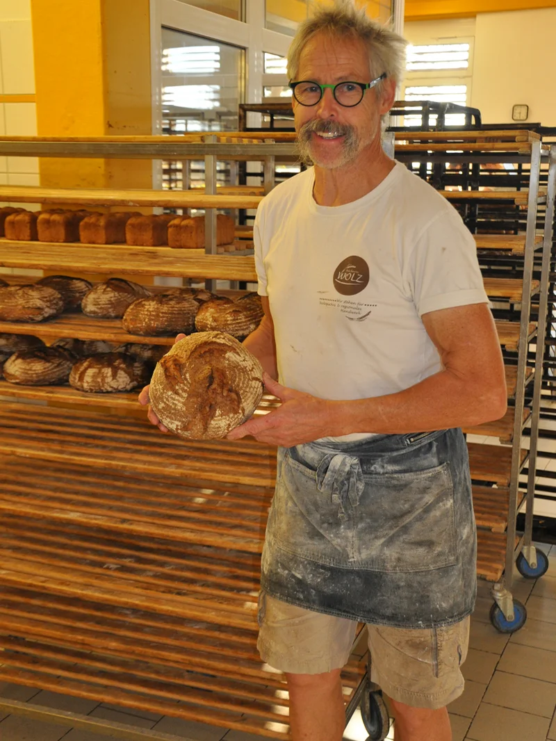 Bäckermeister mit Brot in der Hand. Klick führt zu Großansicht in neuem Fenster.
