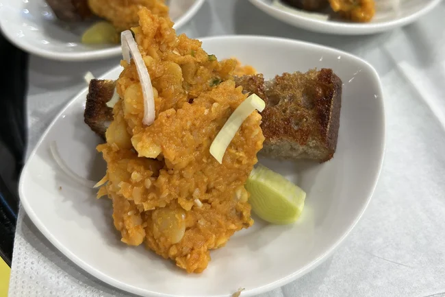 Gelber Erbsenhummus mit geröstetem Landbrot und Olivenöl auf einem Schälchen angerichtet.