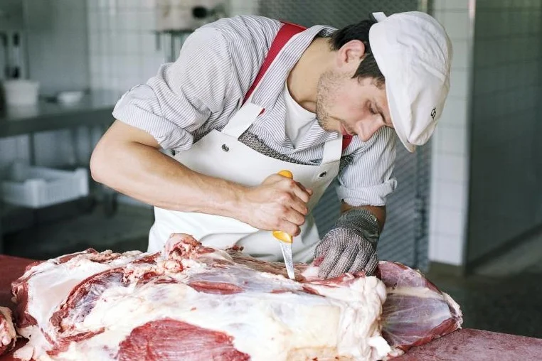 Metzger schneidet ein Stück Fleisch.