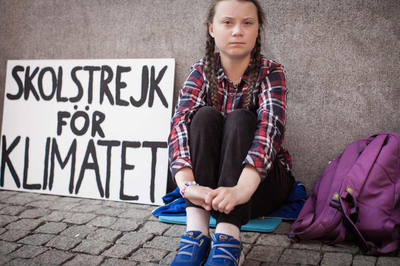 Greta sitzt neben Plakat.