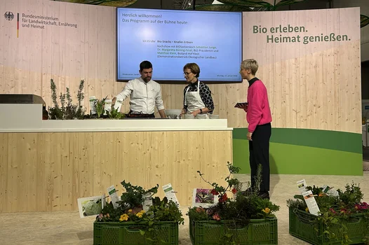 Zwei Frauen und ein Mann stehen vor einer Theke auf der Lebensmittel zubereitet werden