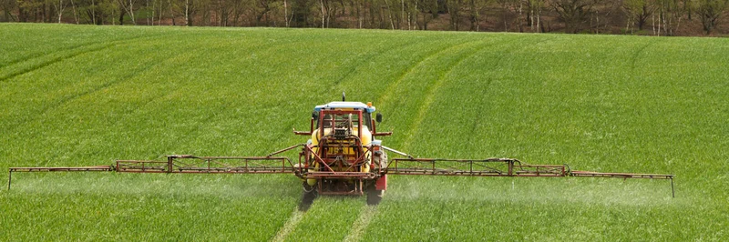 Traktor bringt Pflanzenschutzmittel auf einem Feld aus.