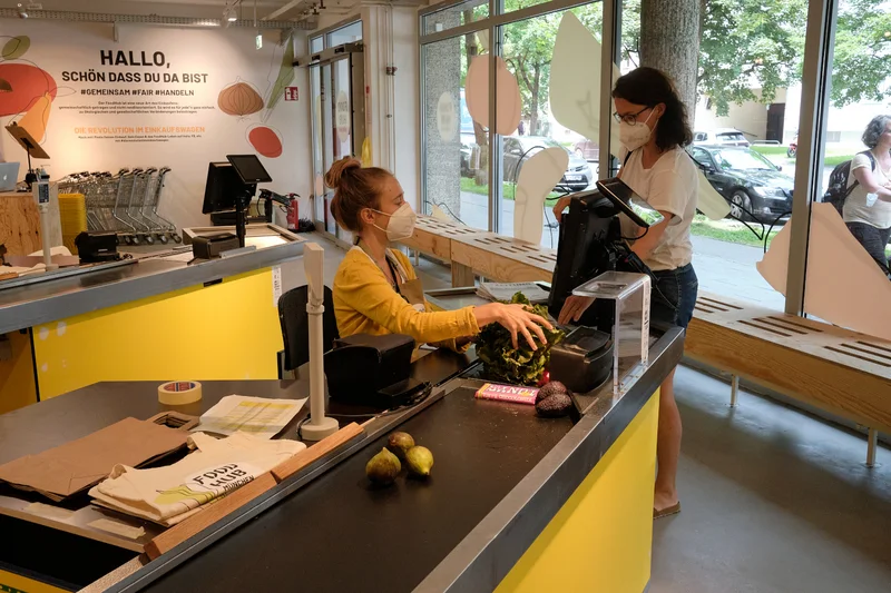 Eine Kassiererin, die eine Kundin an der Kasse bedient. Klick führt zu Großansicht.