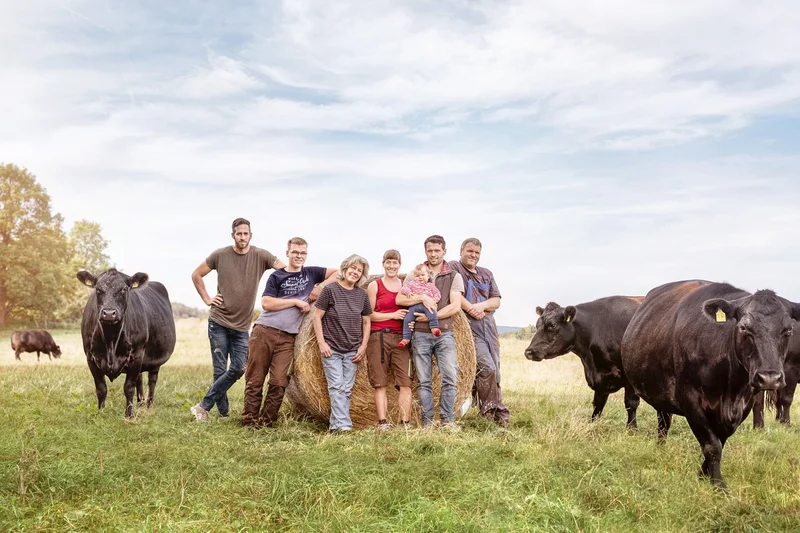 Gruppenbild von Menschen vor einem Heuballen.
