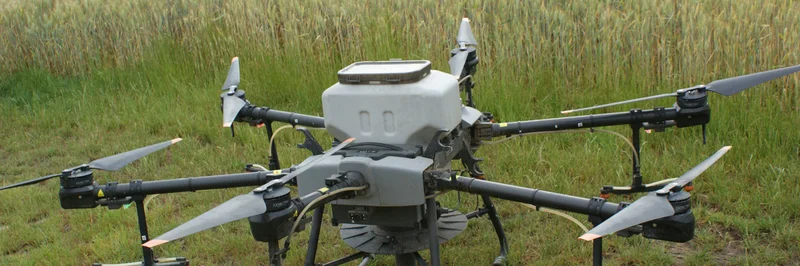 Agrardrohne mit Säaggregat vor Getreidefeld.