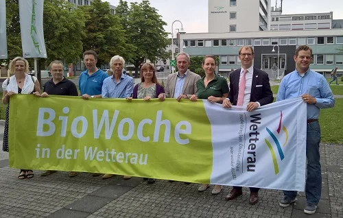Neun Menschen hinter Transparent BioWoche. Klick führt zu Großansicht im neuen Fenster.