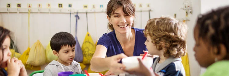 Kinder und Erzieherin beim Essen. Foto: alvarez / iStock / Getty Images Plus via Getty Images