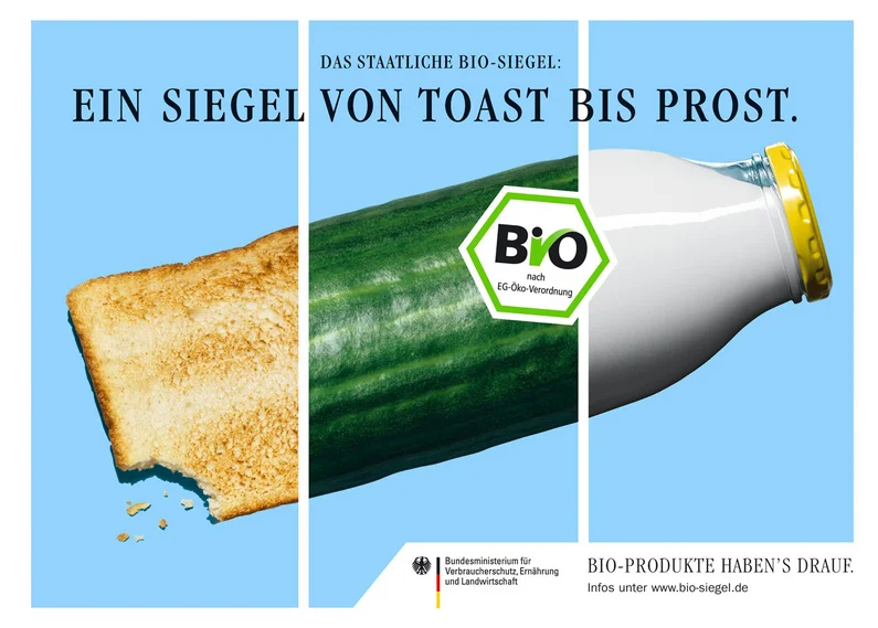 Plakat mit Ausschnitten von Toast, Gurke und Milchflasche, darüber steht "Ein Siegel von Toast bis Prost"
