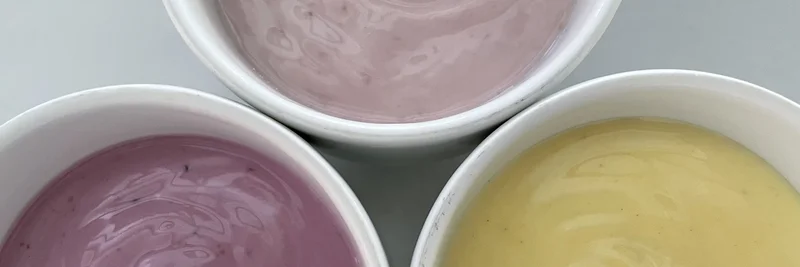 Drei verschiedenfarbige Fruchtjogurts in einem Becher.