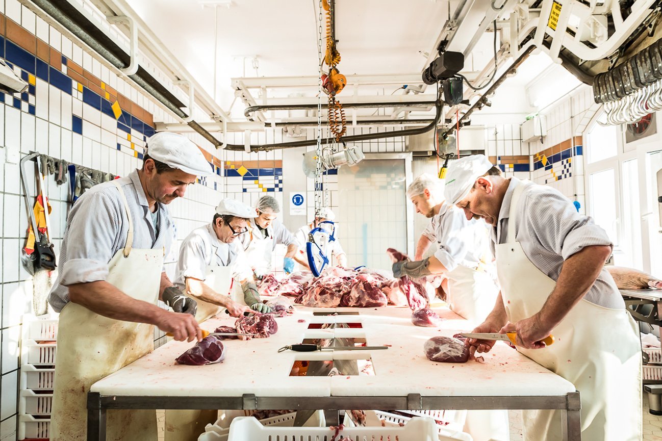 Mitarbeitende verarbeiten Fleisch in der Metzgerei.