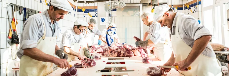 Mitarbeitende verarbeiten Fleisch in der Metzgerei.