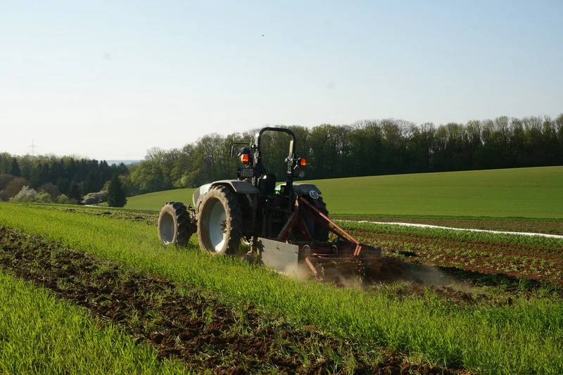 Alt-Text: Bio-Landwirt mit Schlepper bei Bodenbearbeitung. Klick führt zu Großansicht im neuen Fenster.
