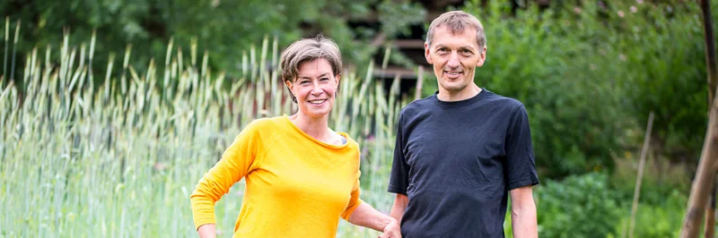 Mann und Frau mit Schubkarre in einem Garten.