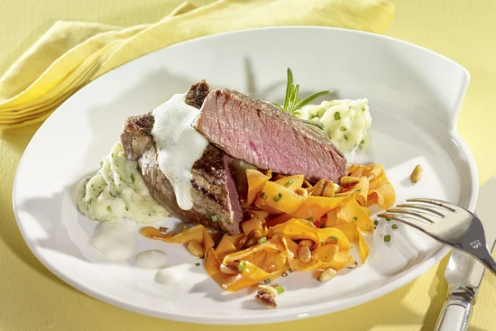 Filet vom Rind mit gebratenen Karotten, weißem Rosmarinschaum und Kartoffel-Kräuterstampf auf Teller angerichtet.