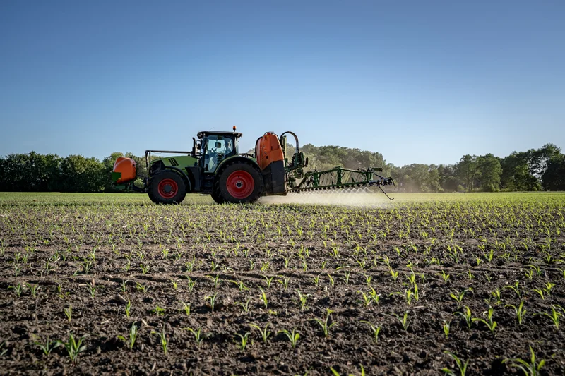 Traktor auf einem Feld beim Ausbringen von Pflanzenschutzmitteln. Klick führt zu Großansicht.