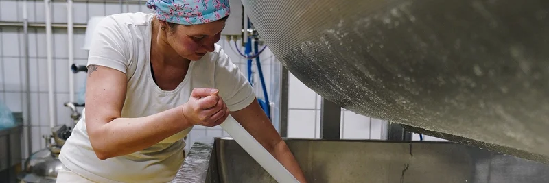 Eine Frau in einer Molkerei, die Milch rührt.