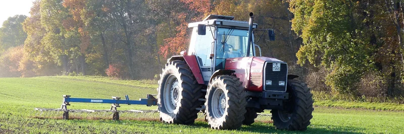 Traktor beim Striegeln auf dem Acker.