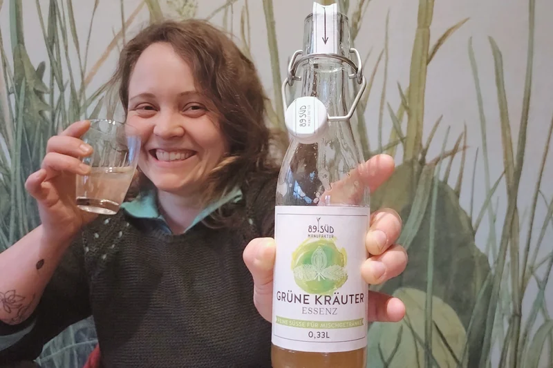 Lucia Birkmeir, Ökojunglandwirtin, hält eine Flasche "Grüne Kräuter".